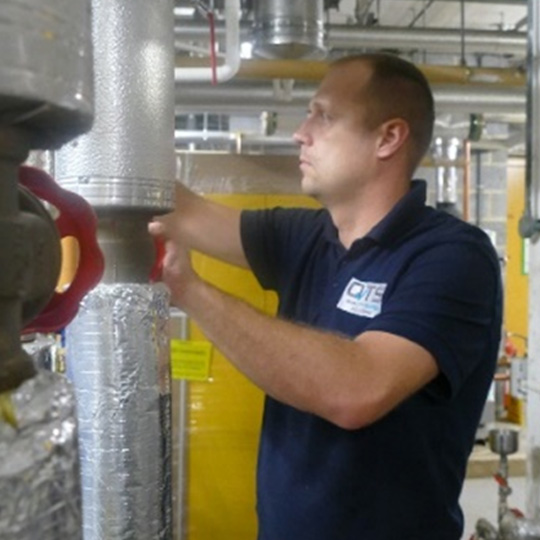 A technician wearing a glove adjusts settings on a circuit breaker panel, surrounded by electrical wiring and components.