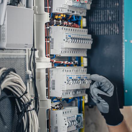 A technician is working on a pipe in an industrial setting, adjusting a valve while ensuring proper insulation and safety measures are in place.